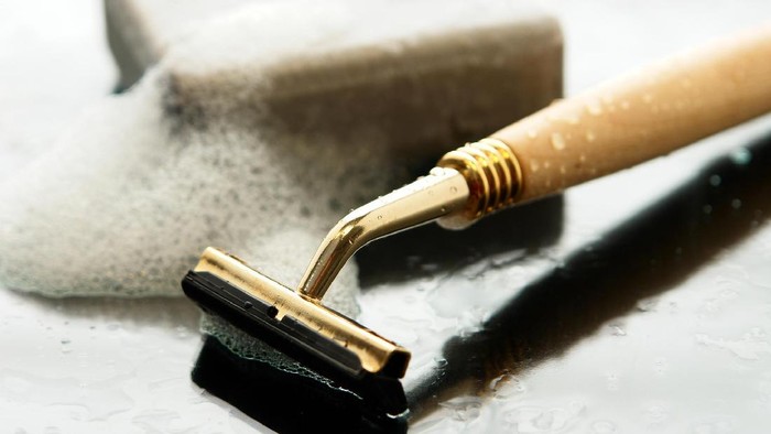146721731 razor, bar of sudsy soap on shiny wet gray surface.