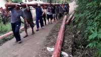 Salah satu cara yang dilakukan apabila akses jalan tidak bisa dilalui kendaraan bermotor adalah memikul tiang listrik bersama dengan jarak tempuh puluhan kilometer. (dok. PLN Kalselteng)