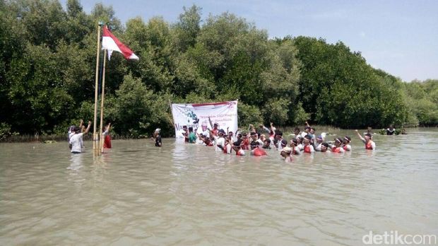 Separuh badan para peserta upacara tenggelam di dalam air. 