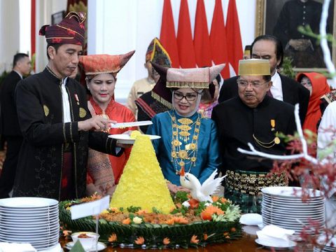 Jokowi sedang memotong nasi tumpeng.