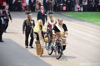 Oso menuntun hadiah sepeda. Di belakangnya ada kapolri dan istrinya yang juga menuntun sepeda.