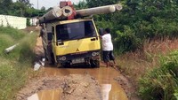 Truk pengangkut tiang listrik melewati jalan berlubang yang tergenang air. (dok. PLN Kalselteng)