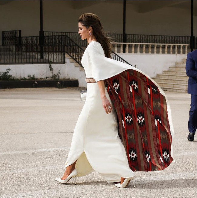 Gaun putih minimalis datang dengan ornamen lengan cape dramatis dan memiliki kejutan motif di baliknya. Foto: Dok. Instagram/Queen Rania Al Abdullah