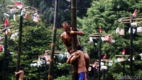 Para peserta berlomba untuk mendapatkan hadiah dengan cara memanjat batang bambu.