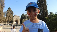Bendera itu kemudian disandingkan dengan bendera Palestina di sebelahnya. Anak-anak itu tampak ceria dan tersenyum bersama.