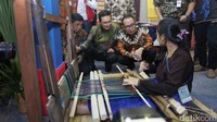 Perajin tenun mendemonstrasikan pembuatan kain kepada Hanif dan Fadel Muhammad.