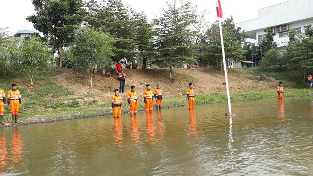 Petugas upacara memakai seragam pasukan oranye dan berpeci