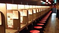 Foto: Masuk ke dalam restoran, pengunjung akan dihadapkan pada ruangan panjang dengan bilik-bilik serta jajaran kursi di sisi kanan. Di antara bilik-bilik tersebut, disekat oleh sebuah pembatas kayu. Tampak juga deretan menu yang tertempel di dinding bilik (Facebook/Ichiran Ramen)