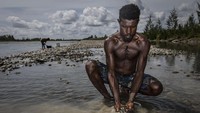 Pemuda suku Komoro juga tidak mau ketinggalan mencari peruntungan dengan menyapih pasir sungai yang mengandung emas. Ulet Ifansasti/Getty Images.