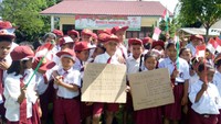 Seusai upacara Hari Kemerdekaan 17 Agustus 2017, murid-murid SD kembali berfoto dengan memegang dua potongan kardus. Potongan kardus pertama bertuliskan: Terima kasih Pak Presiden atas PLN yang sudah tersambung ke desa kami desa Tomuan Holbung Merdeka. (Dok. Kementerian ESDM)