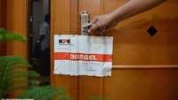 Tampak ada 2 anggota tim KPK yaitu seorang pria dan seorang wanita yang menempelkan stiker bertuliskan Disegel KPK pada pintu