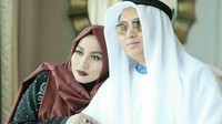 Andika tampak berpakaian seperti di Arab dan memakai kacamata hitam. Anniesa yang berkerudung cokelat menyandarkan kepala di bahu sang suami (Foto: Dok. Istimewa)