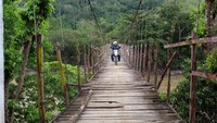 Petugas PLN melintasi jembatan gantung menuju Desa Tallubamba, Enrekang. (Dok. PLN)