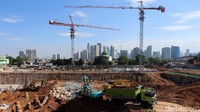 Di belakangnya tampak gedung pencakar langit di kawasan Rasuna Said, Kuningan.