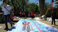 Seorang warga melintas dekat spanduk karnaval yang belum dipasang. Foto: Wisma Putra/detikcom