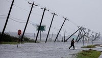 Seorang pria berjalan menerjang badai menuju jalan utama setelah mensurvei propertinya di Rockport (Dok. REUTERS/Adrees Latif)