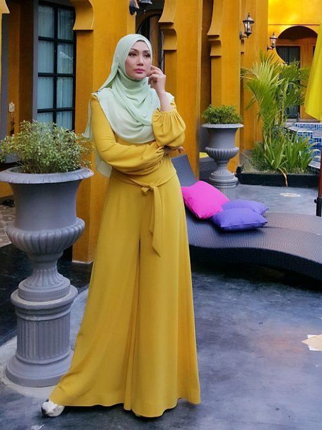 Kali ini Erra Fazira menggunakan jumpsuit kuning dan mengombinasikannya dengan jilbab tosca yang kontras. Foto: Dok. Instagram @errafazira