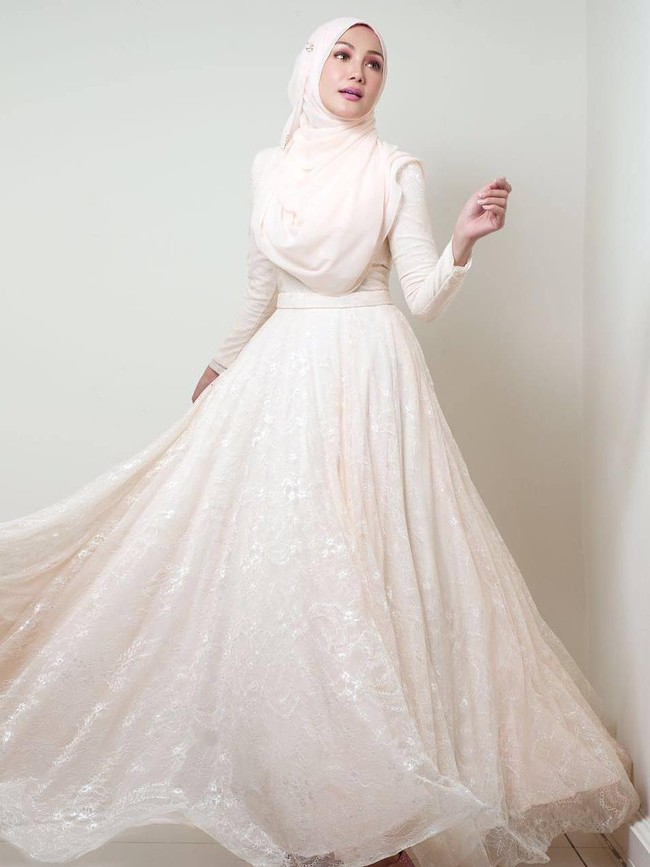 Erra Fazira terlihat anggun mengenakan gaun berpotongan rok flare warna putih gading. Gaya hijabnya tetap simpel dan elegan. Foto: Dok. Instagram @errafazira