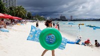 Lihat saja pantai-pantai di Guam, masih penuh dengan wisatawan. Turis cewek ini saja masih asyik menenteng ban pelampung. Padahal kabar terakhir, Korut sudah meluncurkan 3 rudal pada Sabtu (26/8) kemarin (Erik De Castro/Reuters)