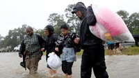 Warga Houston membawa pakaian mereka dengan kantong plastik saat dievakuasi dari banjir. Foto: REUTERS/Jonathan Bachman