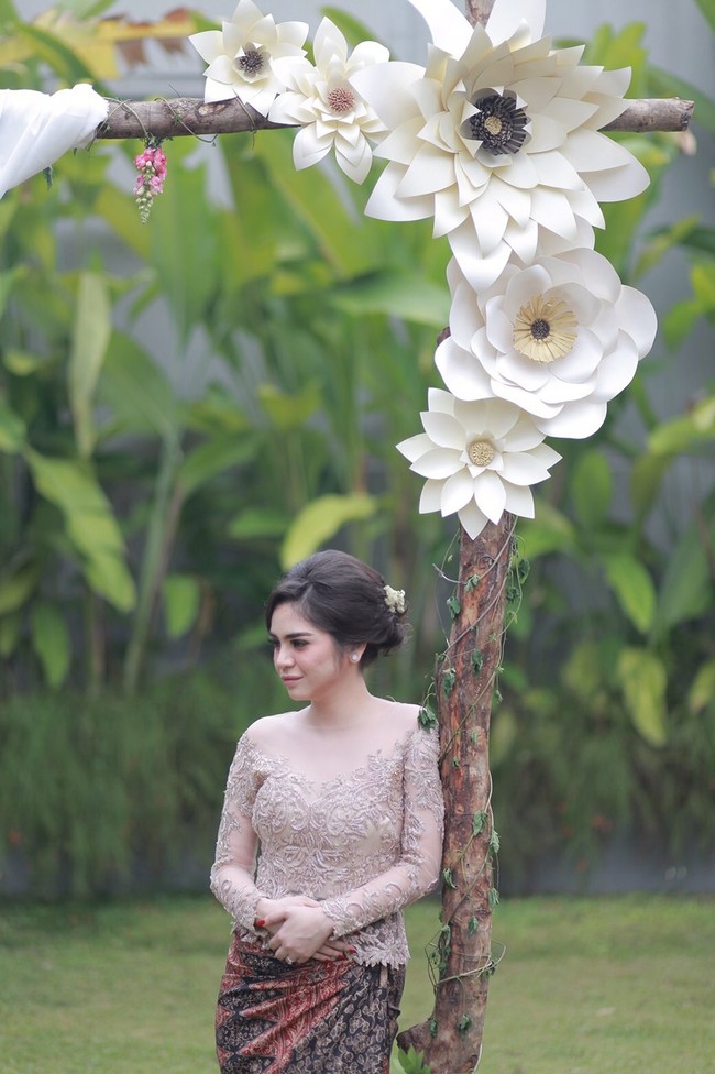 Paper flower tidak harus selalu ditempel sebagai backdrop. Anda juga bisa menaruhnya sebagai pemanis di tempat lain, seperti batang pohon ala Angela dan Ajat ini. Dekorasi paper flower berikut cocok jadi inspirasi lamaran atau pernikahan outdoor. (Foto: Bride Dept)