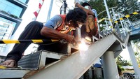 Pekerja tengah menyelesaikan pembangunan halte baru TransJakarta.
