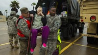 Tentara Angkatan Laut Texas terlihat menggendong soerang nenek berusia 81 tahun untuk turun dari truk usai dievakuasi.