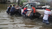 Beberapa warga nampak bergotong-royong membantu memindahkan sebuah mobil yang mogok.