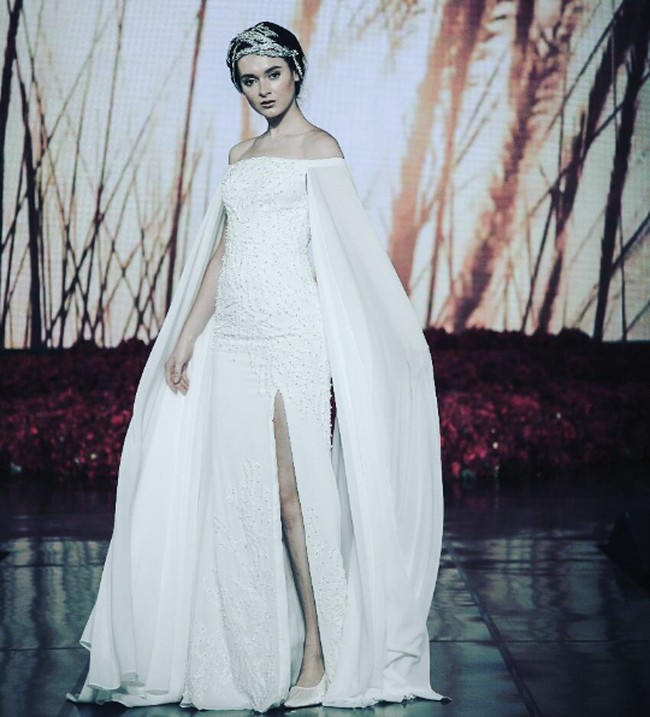 Rancangan Ivan Gunawan bisa jadi pilihan bila ingin tampil mewah di hari pernikahan. Untuk Raisa, gaun off the shoulder dengan tambahan cape megah berikut akan membuat ia tampil mempesona.