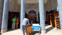 Seorang jemaah mengisi kotak amal masjid.