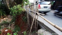 Warga memasang bambu agar kendaraan tidak terperosok ke dalam kali Krukut.