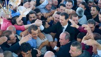 Tayangan televisi nasional Suriah menunjukkan Assad tersenyum di hadapan para pendukungnya, yang memenuhi bagian dalam masjid. Foto: SANA/Handout via REUTERS