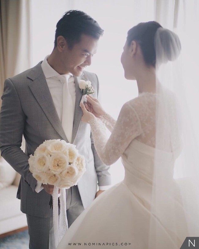Di hari pernikahan, Fiona dan Dion sama-sama tampil menawan. Setelan berwarna abu-abu dan kemeja putih serta dasi putih yang dikenakan Dion berpadu manis dengan gaun indah Fiona. Foto: Dok. Instagram Bride Story/Nomina Pics