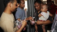 Sebagian warga antre sambil menggendong anaknya.