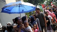 Sebagian warga memakai payung untuk menghindari terik sinar matahari.