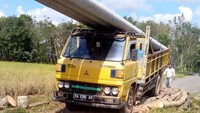 Truk bermuatan material listrik melewati jembatan yang terbuat dari pohon kelapa. (Dok. PLN Kalselteng)