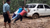 Petugas PLN mendorong mobil yang terjebak di jalan berlumpur. (Dok. PLN Kalselteng)