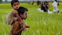 Anak laki-laki Rohingya yang menggendong adiknya saat menyeberangi kanal. (Foto: Mohammad Ponir Hossain/Reuters)