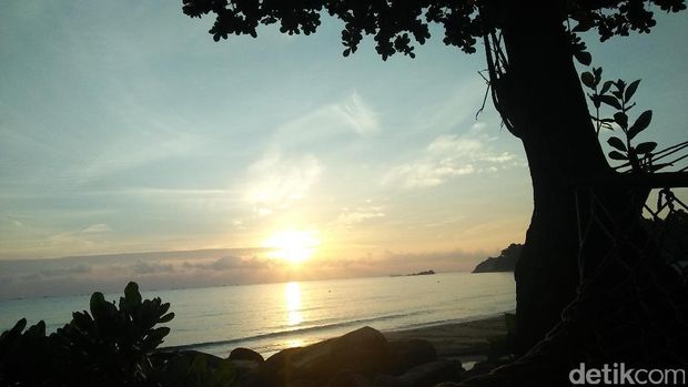 Menikmati sunrise dari hammock di pinggir pantai