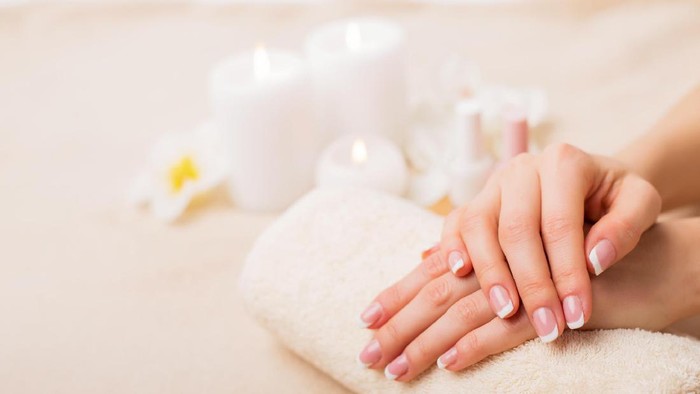 Tes Kepribadian Kuku Closeup of nicely manicured female fingernails. One hand is placed on top of other, both on a white towel. Very nice french manicure with transparent nail paint. Blurry beige background. Copy space.
