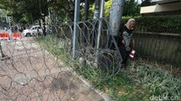 Seorang warga yang akan lewat tampak kesulitan dan harus minggir melalui taman.