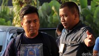 Seorang pria yang mengenakan kaus berwarna hitam juga tampak dikawal masuk ke gedung KPK.