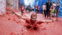 Traveler ini terlihat gembira banget bisa mandi lautan tomat di Festival La Tomatina. Festival ini jadi atraksi yang menarik wisatawan untuk liburan ke Spanyol (Heino Kalis/Reuters)