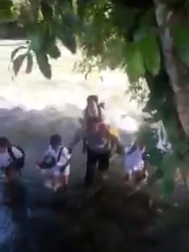 Polisi Bantu Bocah SD Seberangi Sungai