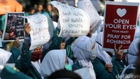 Massa aksi tampak memperlihatkan tulisan-tulisan di poster dan spanduk yang mereka bawa.