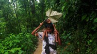 Seorang warga melindungi anaknya dari guyuran hujan dengan menggunakan daun. Danish Siddiqui/Reuters.