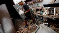 Dengan kepala dibalut perban, seorang warga berusaha mengumpulkan barang-barang yang masih bisa diselamatkan di reruntuhan bangunan. Edgard Garrido/Reuters.