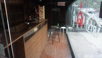 Pintu toko terlihat terkunci rapat dan terdapat tulisan closed di dinding kaca. Namun di bagian bawah dekat pintu terdapat lubang yang ditutup dengan kardus berwarna coklat.  