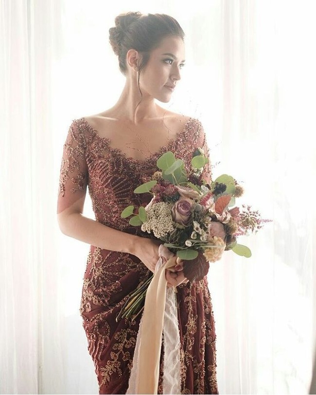 Gaun dengan potongan kerah V ini nampak mengaksentuasi leher jenjang Raisa. Gaun juga hadir elegan dengan payet bebatuan khas Biyan.  Terbuka sampai bagian bahu membuat leher penyanyi Kali Kedua ini tampak jenjang. Semakin cantik dengan aksen high-slit pada rok. Foto: Instagram