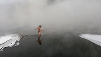 Saking dinginnya, sekitar sungai nampak berkabut. Sekeliling sungai pun di kelilingi dengan salju (Ilya Naymushin/Reuters)